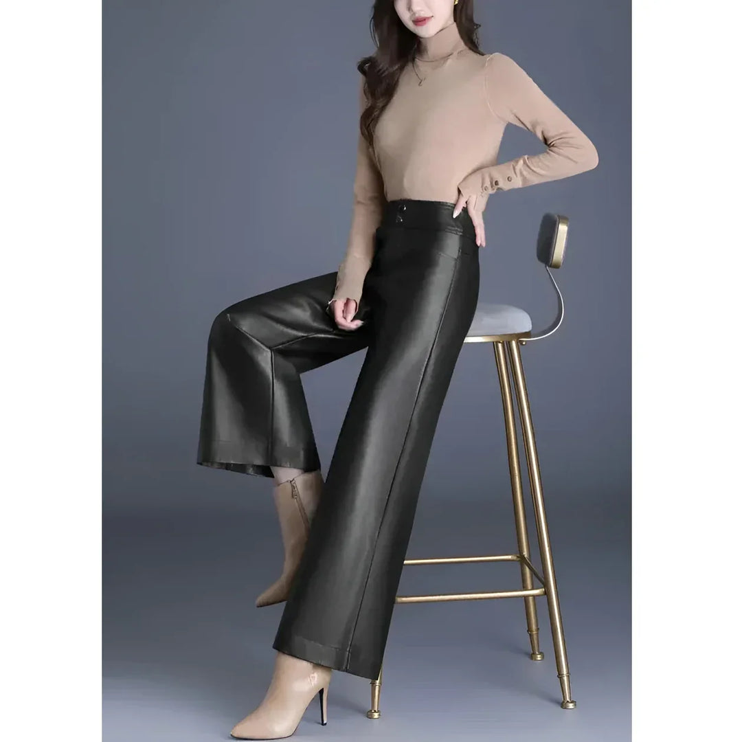 Woman in beige turtleneck and black wide-leg pants sitting on a modern chair, Rovelli fashion