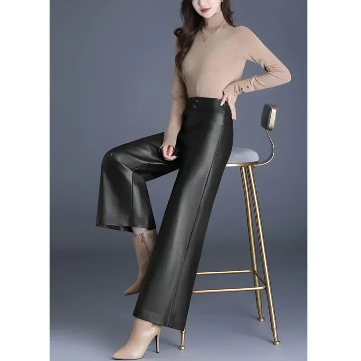 Woman in beige turtleneck and black wide-leg pants sitting on a modern chair, Rovelli fashion