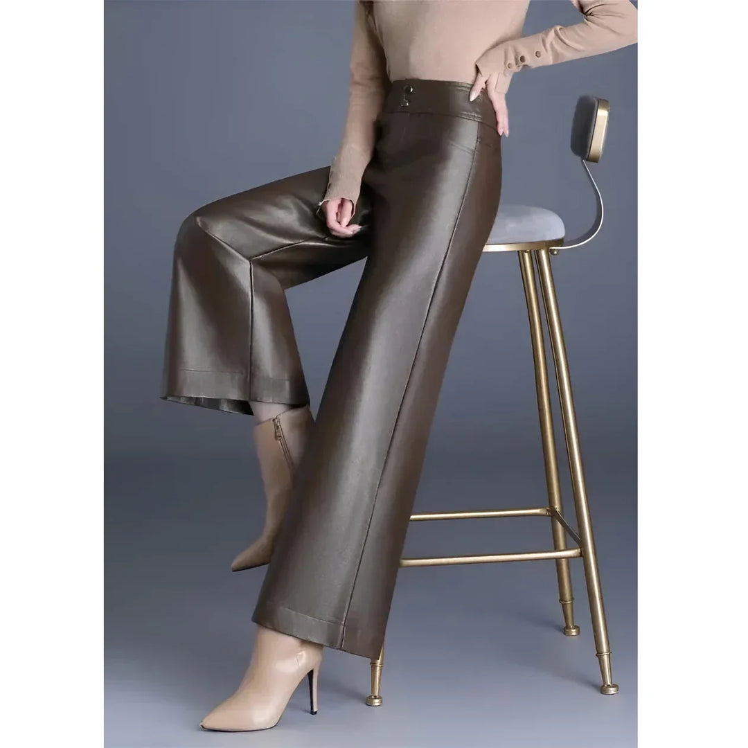 Woman wearing brown wide-leg faux leather pants from Rovelli, seated on gold chair