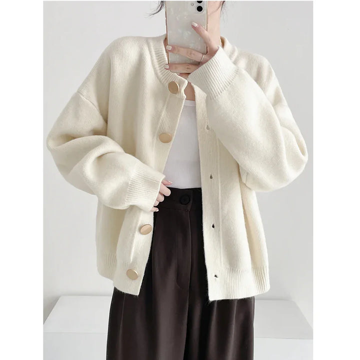 Woman in cream knit cardigan with gold buttons from Rovelli, paired with brown pants