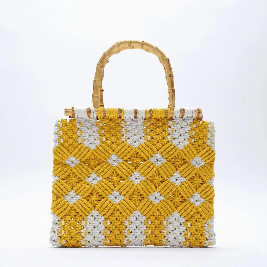 A square macramé handbag featuring a geometric yellow and white woven pattern and stylish bamboo handles, set against a plain white background. This lightweight bag is perfect for adding a modern touch to any outfit.