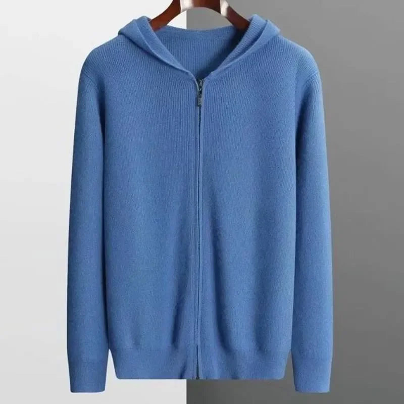 A blue, zip-up hoodie with long sleeves, crafted from luxurious cashmere, is displayed on a hanger against a background split between white and gray.
