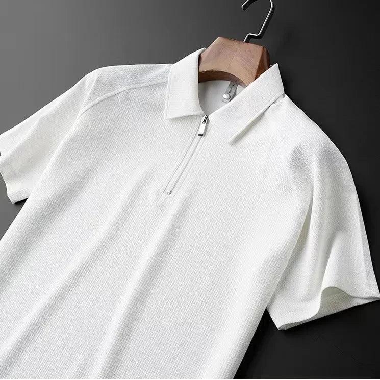 A white short-sleeve mens silk polo with a textured, moisture-wicking fabric, featuring a partial front zipper, displayed on a wooden hanger against a dark background.