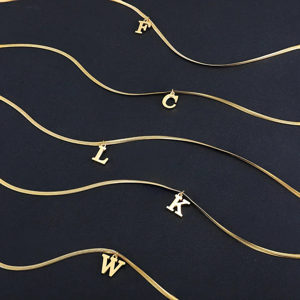 Gold initial letter necklaces with F, C, L, K, W charms on black background, Rovelli jewelry