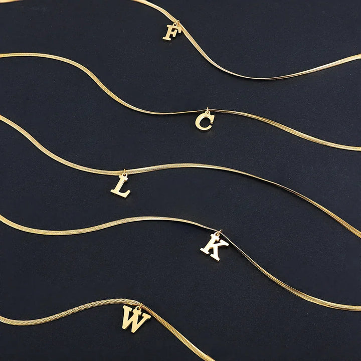 Gold initial letter necklaces with F, C, L, K, W charms on black background, Rovelli jewelry