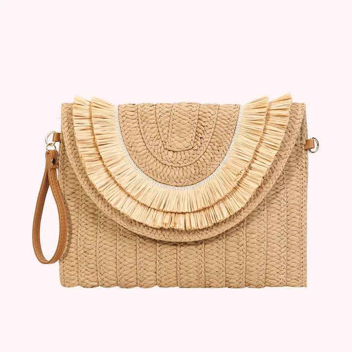 Rovelli woven straw clutch bag with wrist strap and fringe detailing on a light background