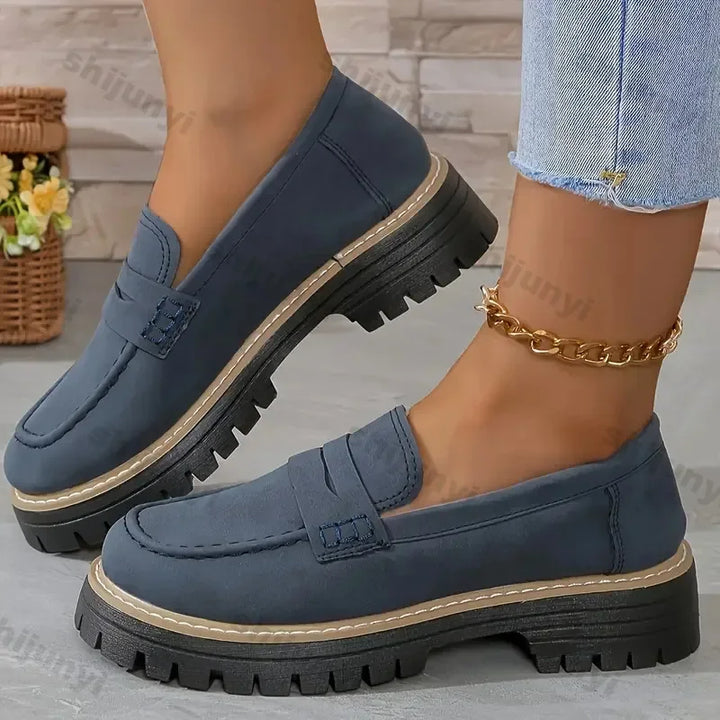 Rovelli women’s navy blue chunky loafers with rugged soles, modeled with light jeans indoors.