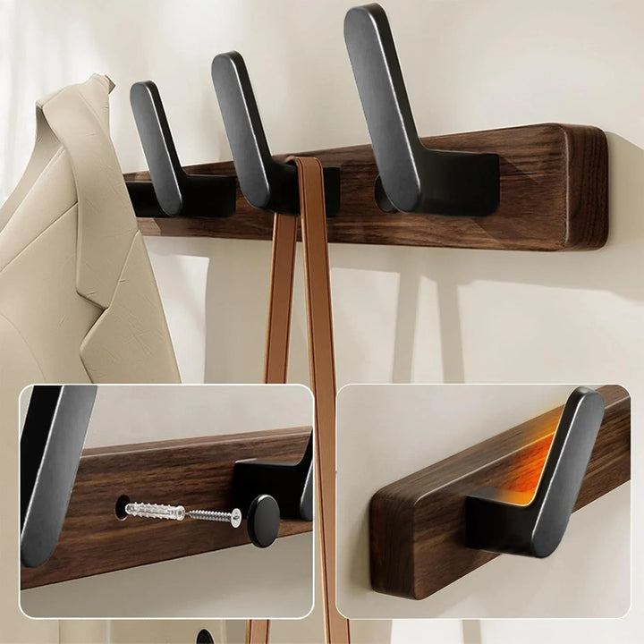 Modern wooden wall-mounted coat rack with black hooks holding a beige jacket and bag