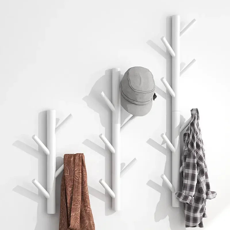 Modern white wall-mounted coat racks shaped like tree branches with jackets and hat, Rovelli