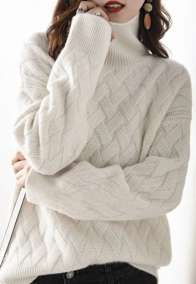 Woman wearing a white, ultra soft cable-knit turtleneck sweater with long sleeves, black pants, statement earrings, and red lipstick, posing with one hand near her face against a white background.