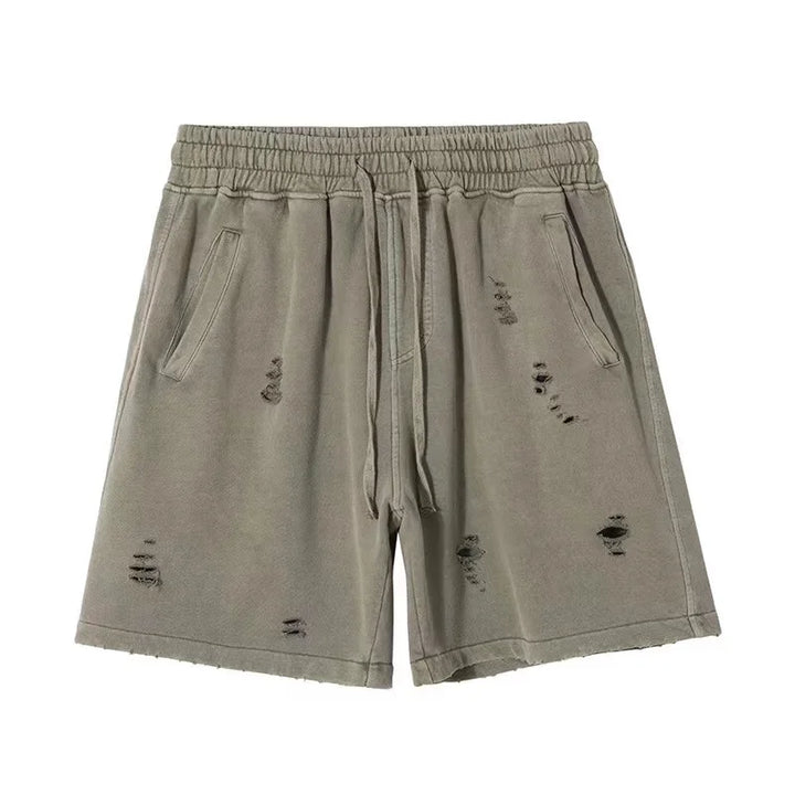 Light olive green vintage baggy shorts with an elastic waistband, drawstring, side pockets, and a cut-up design featuring distressed, ripped details on the front.