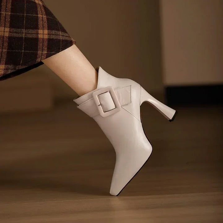 Rovelli beige ankle boot with high heel and large buckle, plaid skirt, wooden floor