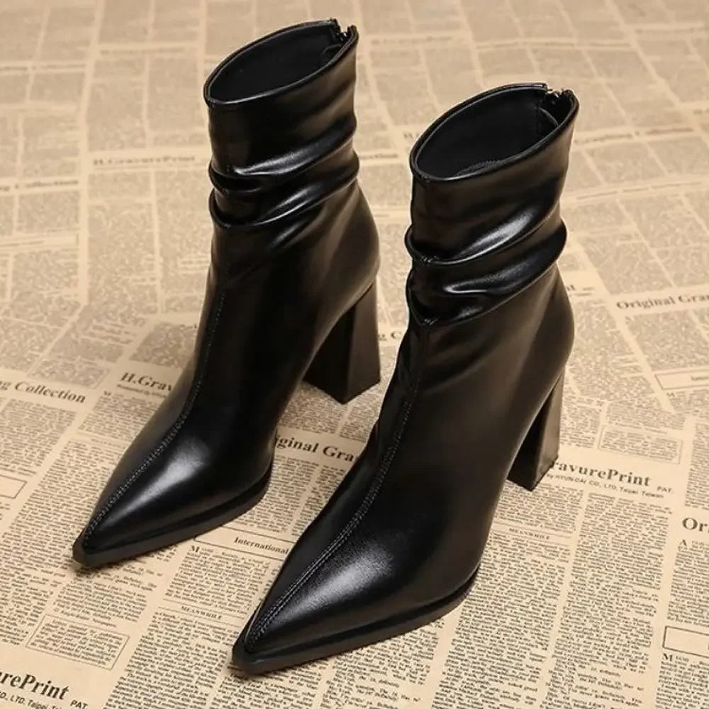 Rovelli black high heel ankle boots with pointed toe on newspaper background
