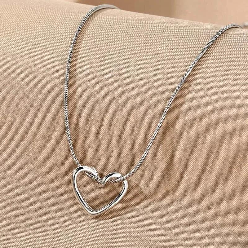 Rovelli silver heart pendant necklace on beige fabric background