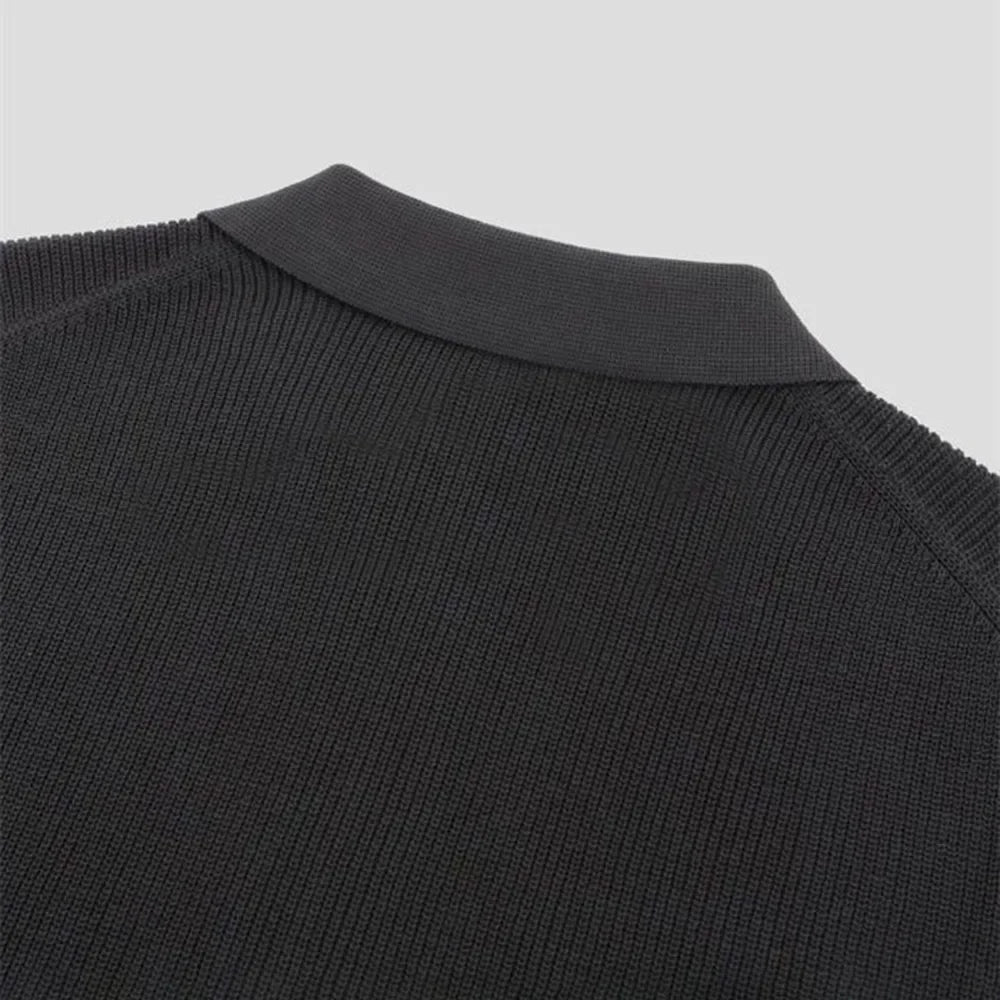 Close-up of the upper back and collar of a black knitted sweater, showing the texture of the fabric and ribbed detailing on the crew neckline against a plain light background.