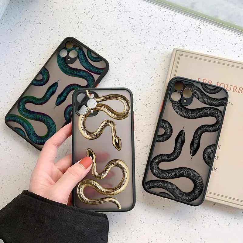 Rovelli snake print phone cases in gold, black, and green on white surface next to book