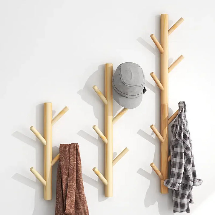 Rovelli wooden wall hooks in branch design holding a hat, shirt, and scarf on white wall