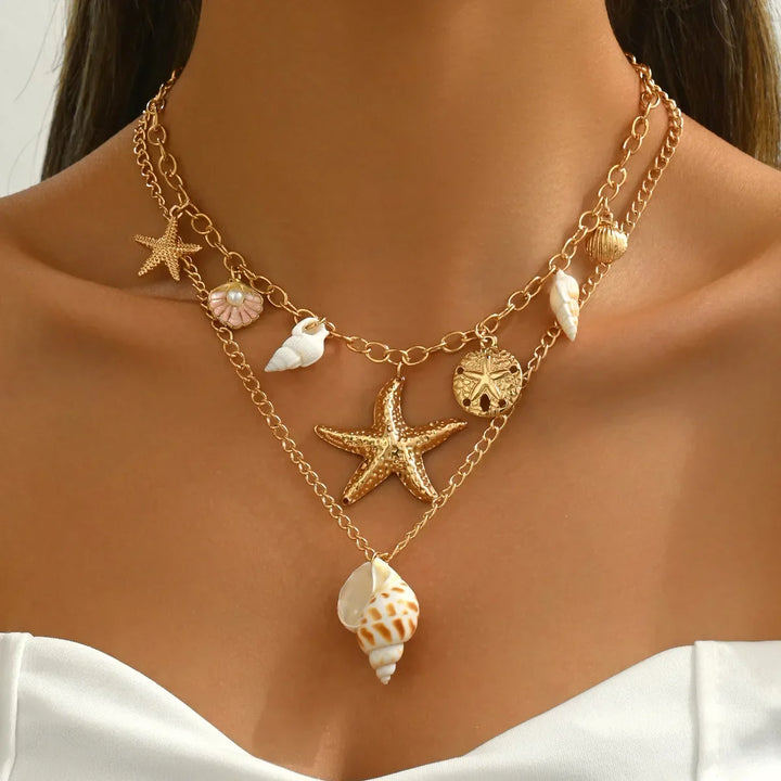 Rovelli layered gold necklace with starfish, shell, and sand dollar charms on model's neck