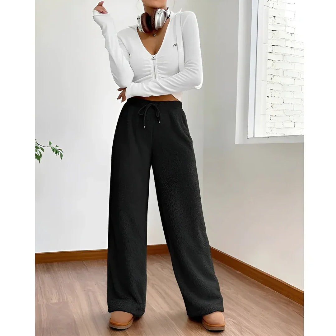 Rovelli model in white cropped zip top, black wide-leg pants, and headphones indoors