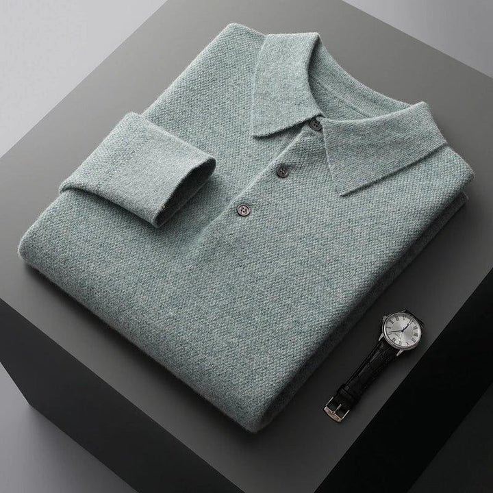 Folded grey knit polo shirt with buttons next to a wristwatch on a grey surface, Rovelli style