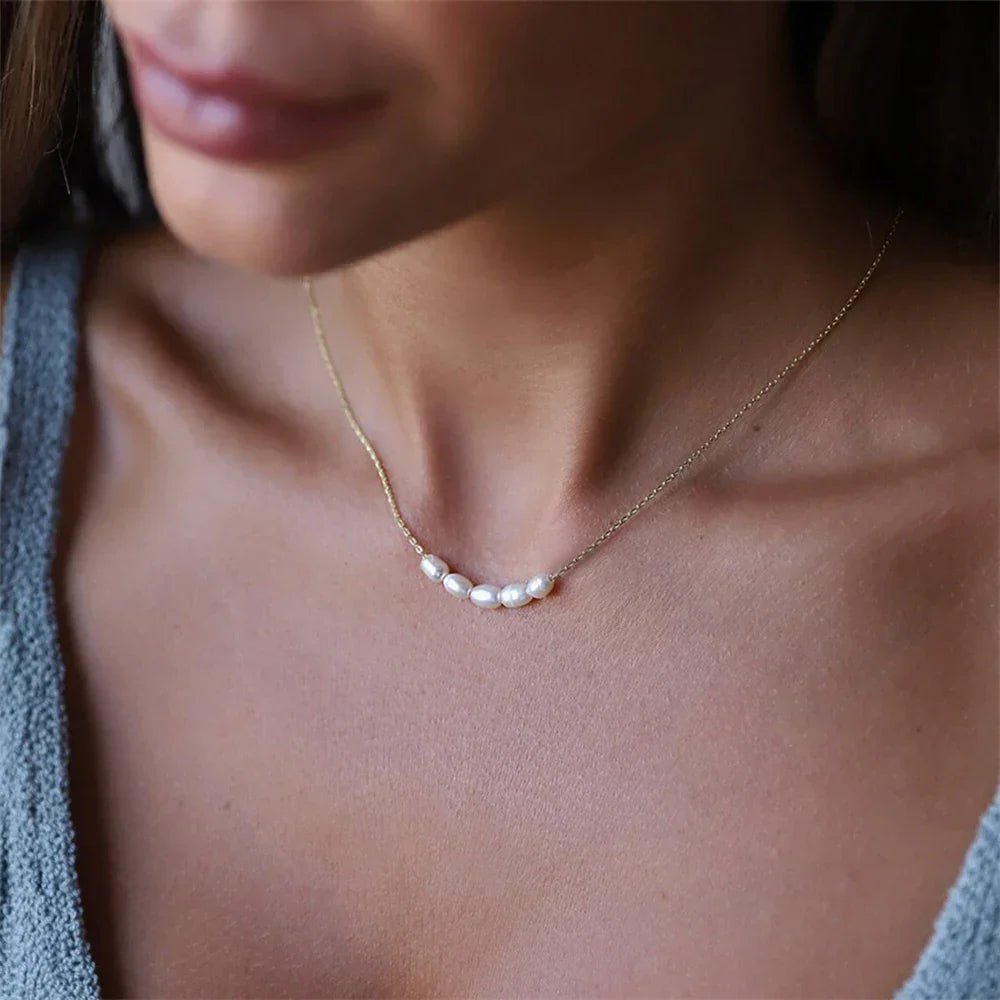 Rovelli delicate gold necklace with five freshwater pearls on a woman's neck