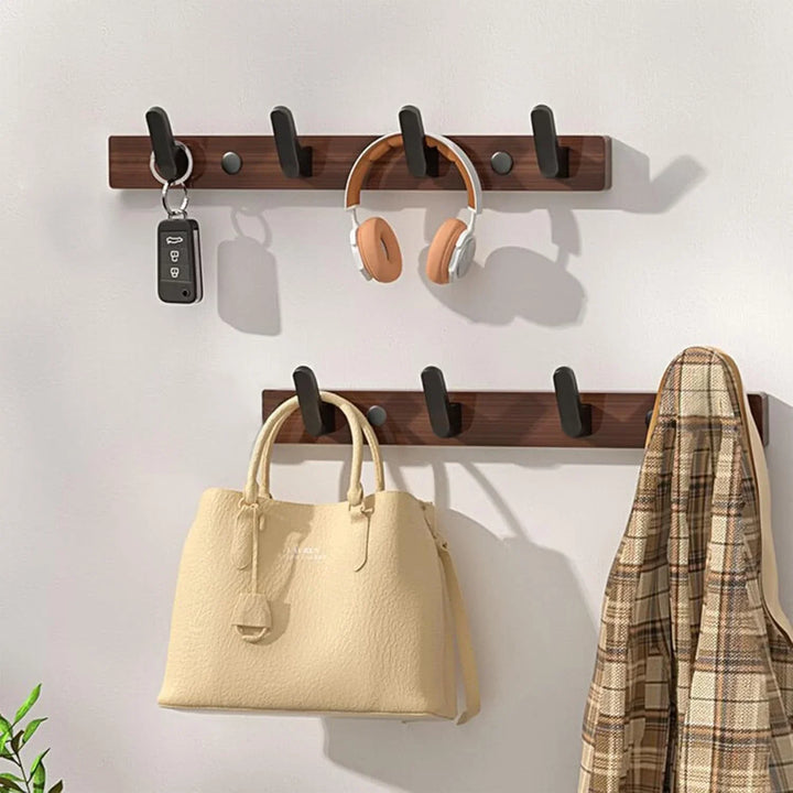 Modern wall hooks with a beige handbag, plaid coat, headphones, and car keys, Rovelli decor