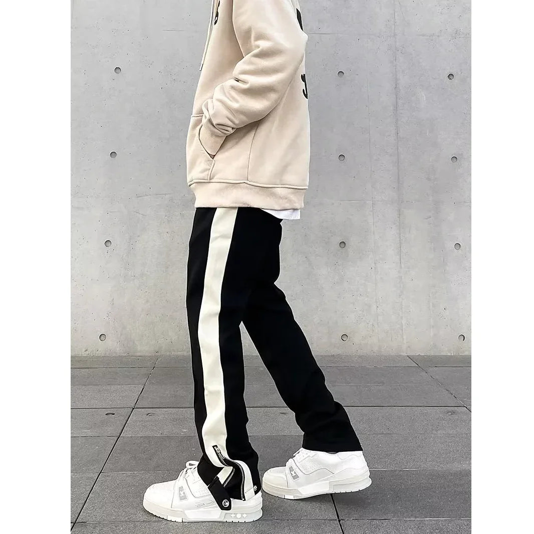 Side view of person in beige hoodie, black and white track pants, and white sneakers, Rovelli