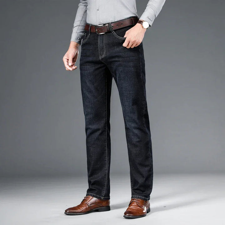 Man wearing dark blue jeans, brown belt, dress shoes, and grey shirt, Rovelli fashion.