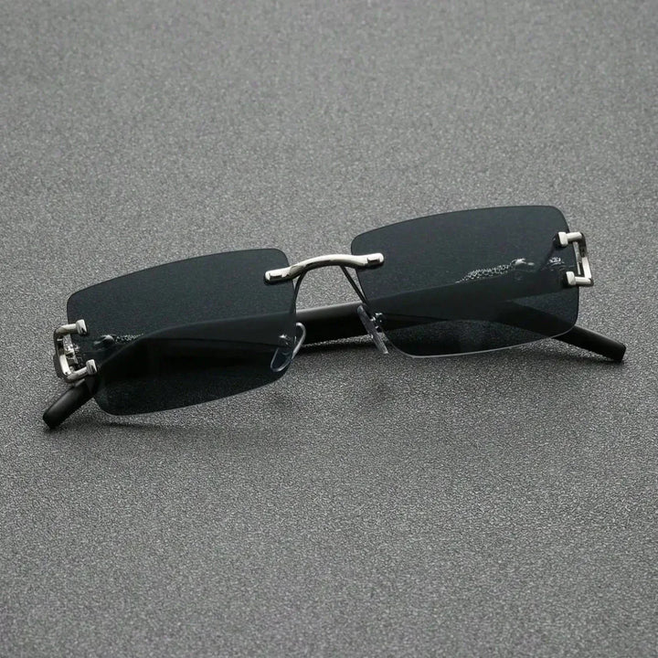 A pair of rectangular, rimless black sunglasses with durable hinges, metal bridge and temples, resting on a textured gray surface.