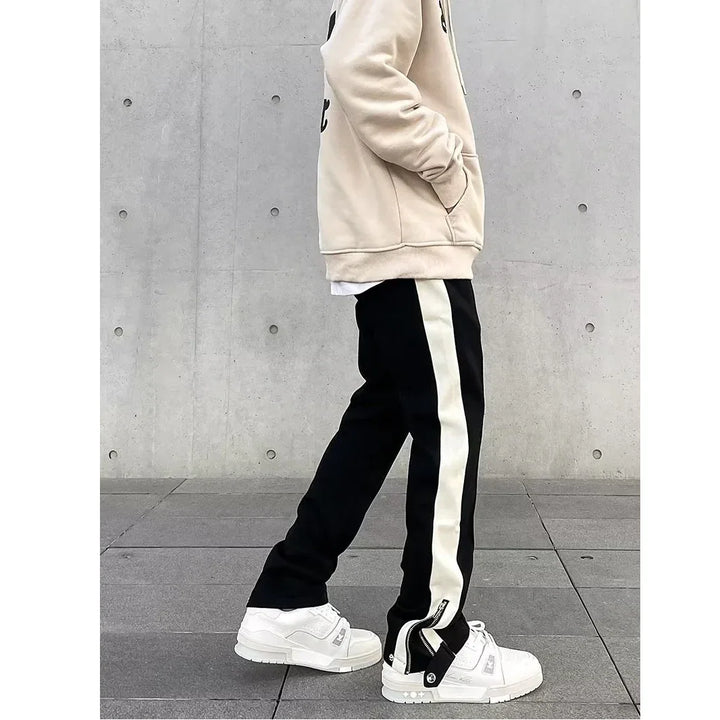 Rovelli casual streetwear outfit with beige sweatshirt, black pants with white stripes, and white sneakers