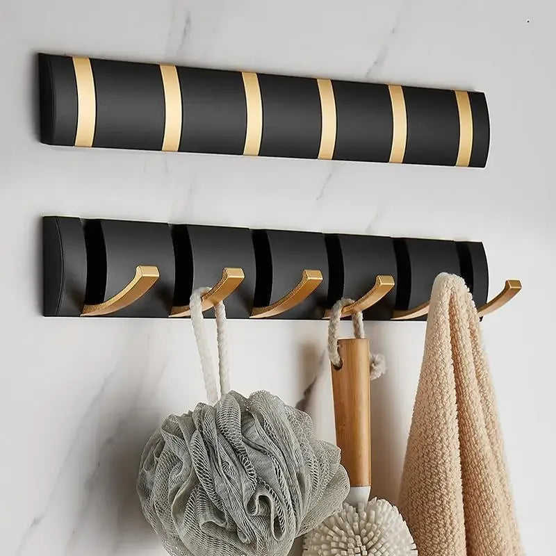 Modern black and gold wall hooks holding bath towels and accessories on marble wall, Rovelli
