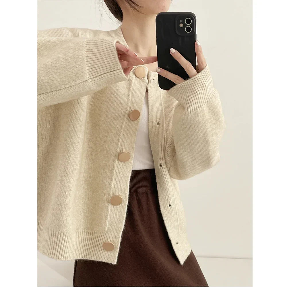 Woman wearing beige knit cardigan with large buttons, white top, and brown skirt, Rovelli