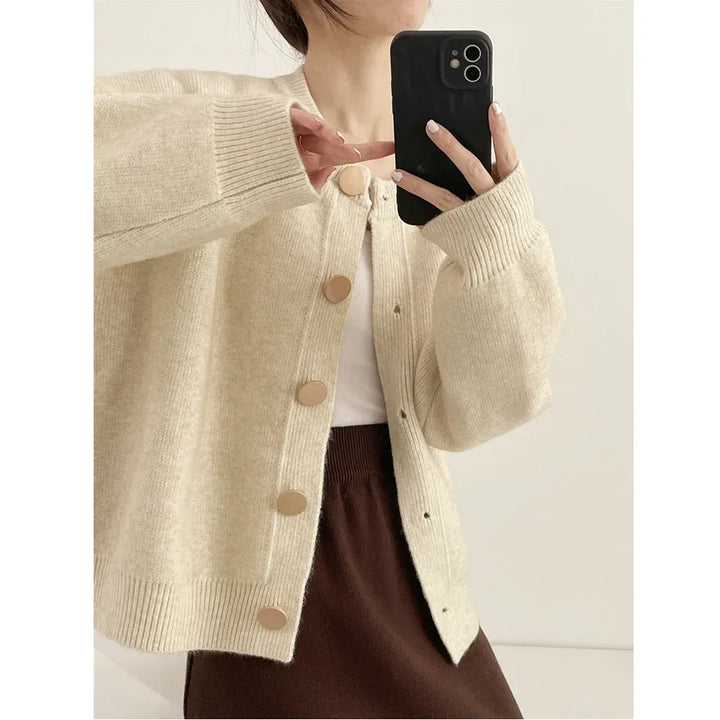 Woman wearing beige knit cardigan with large buttons, white top, and brown skirt, Rovelli