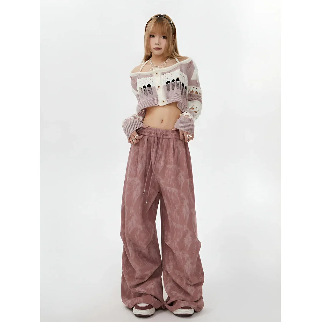 Model wearing cropped knit cardigan and loose pink pants from Rovelli on white background