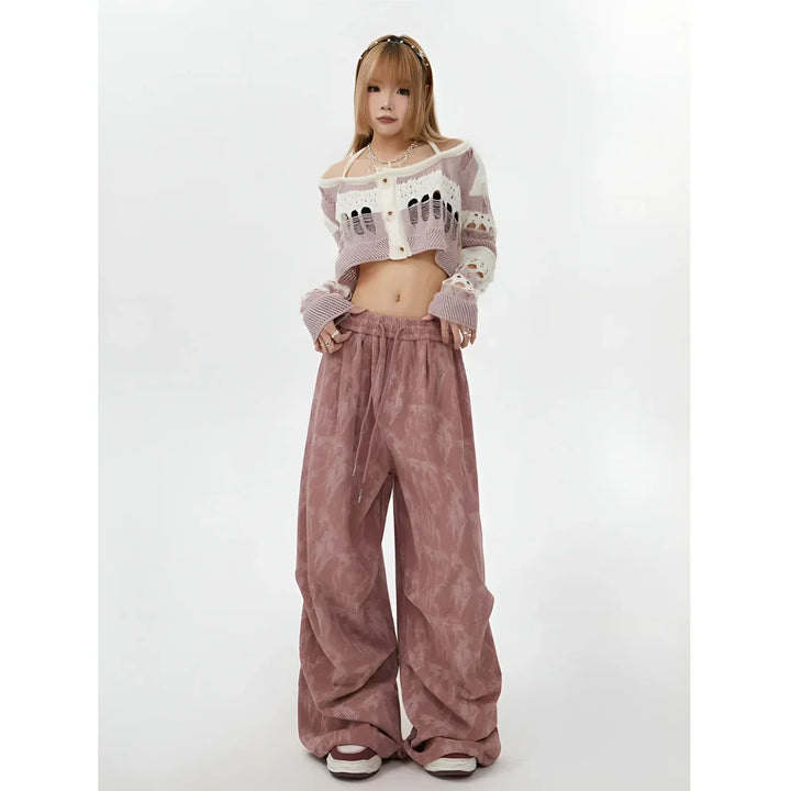 Model wearing cropped knit cardigan and loose pink pants from Rovelli on white background