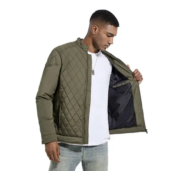 A man wearing a slim-fit, quilted olive green jacket over a white t-shirt and blue jeans stands against a white background, holding the jacket open to show its inner lining.