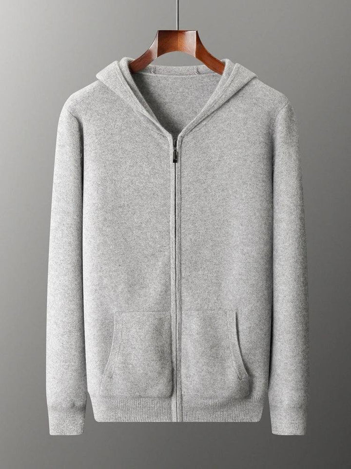 A light gray zip-up hoodie with a hood, front pockets, and ribbed cuffs and hem, displayed on a wooden hanger against a plain gray background—a cozy knit cardigan ideal for cool days.