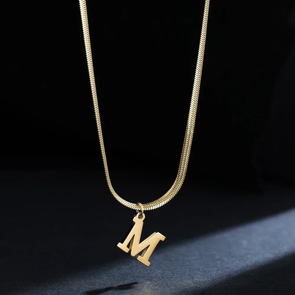 Rovelli gold letter M pendant necklace on black background