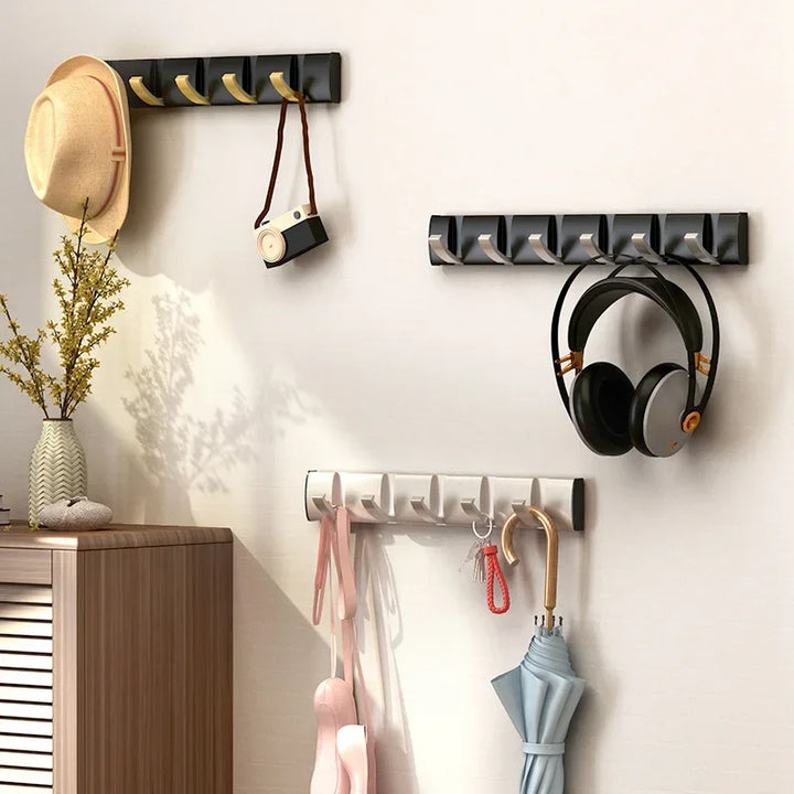 Modern wall hooks in entryway holding hat, camera, headphones, umbrella, bags on white wall