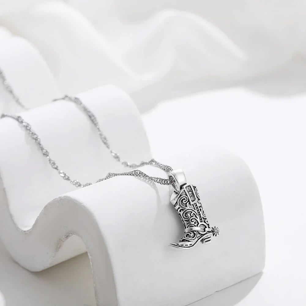 Rovelli silver cowboy boot pendant necklace with ornate design on white display