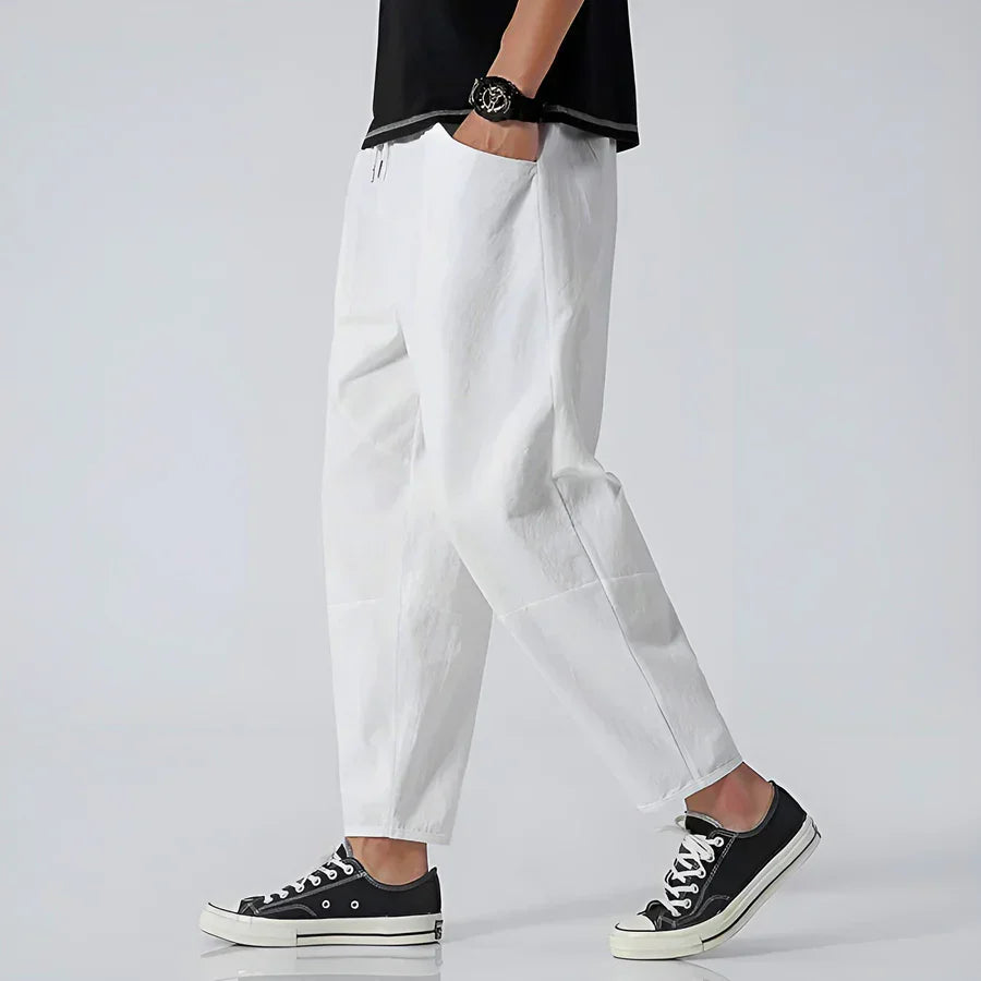 Rovelli casual white pants styled with black sneakers, side view on model