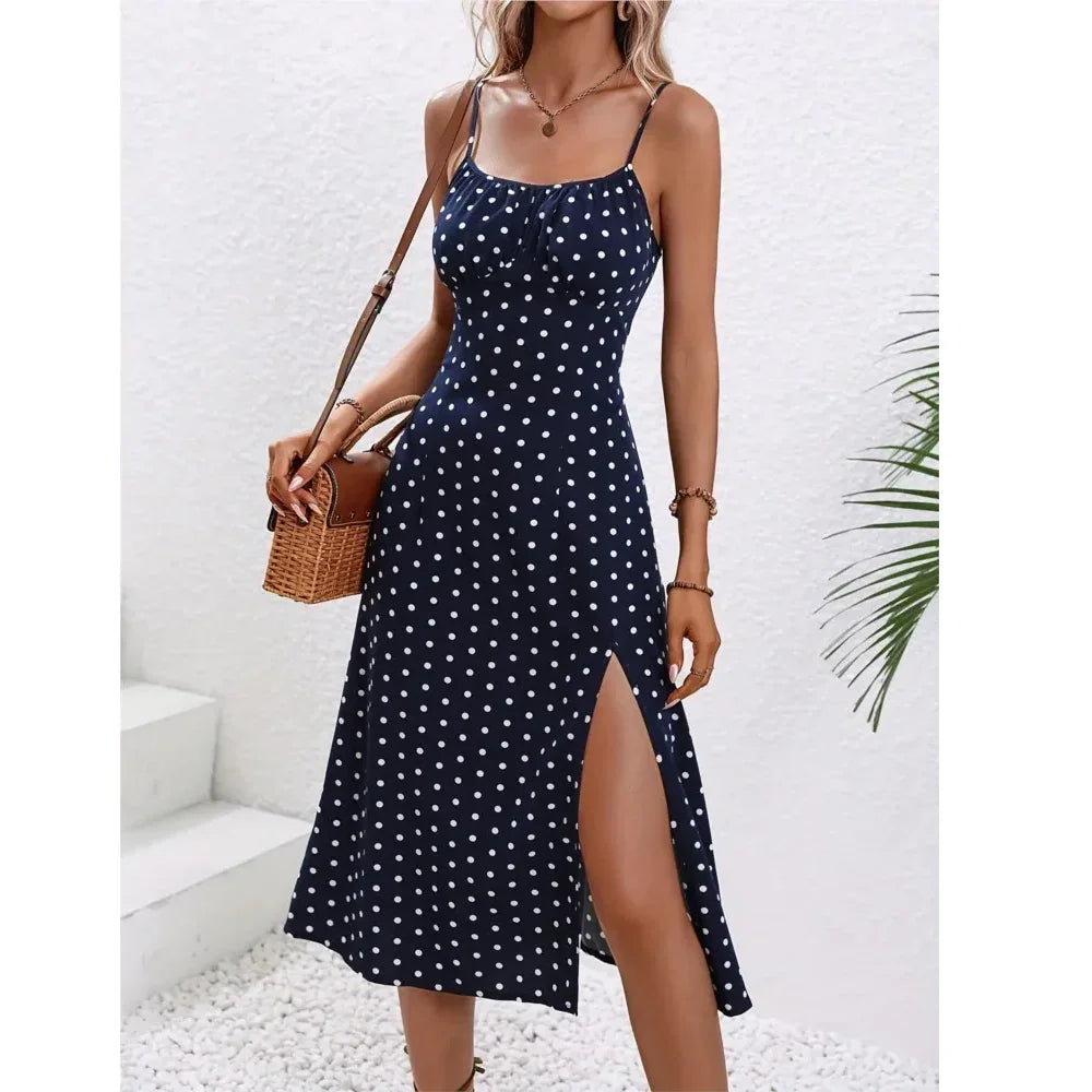 Woman in navy blue polka dot summer dress with side slit, holding woven bag, Rovelli fashion