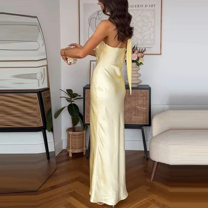Woman in a yellow satin evening gown standing in a modern living room, Rovelli style.