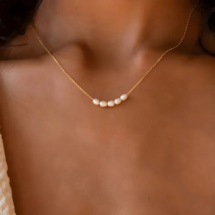 Gold chain necklace with five white pearls on a woman's neck, Rovelli jewelry