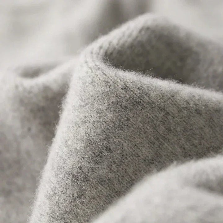 Close-up of soft, light grey Merino wool pants with a fuzzy texture and gentle folds, highlighting the material’s warmth, coziness, and durable construction.