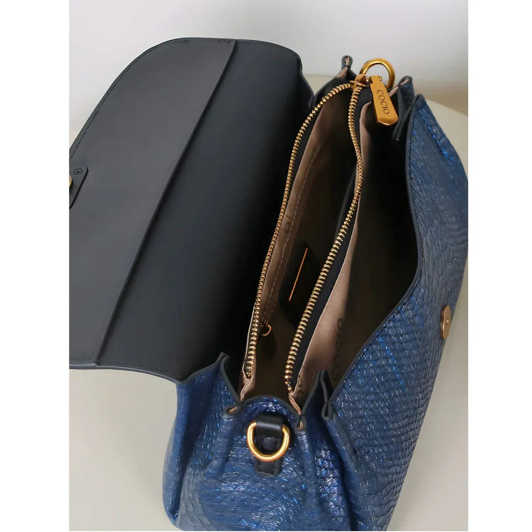 Rovelli blue textured handbag with gold zipper and open flap, showing interior compartments