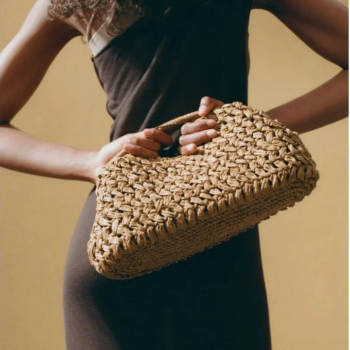 Woman holding a woven straw handbag, stylish accessory by Rovelli
