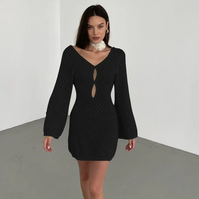 Woman wearing a black textured knit mini dress with long sleeves and front keyhole cutouts, Rovelli style