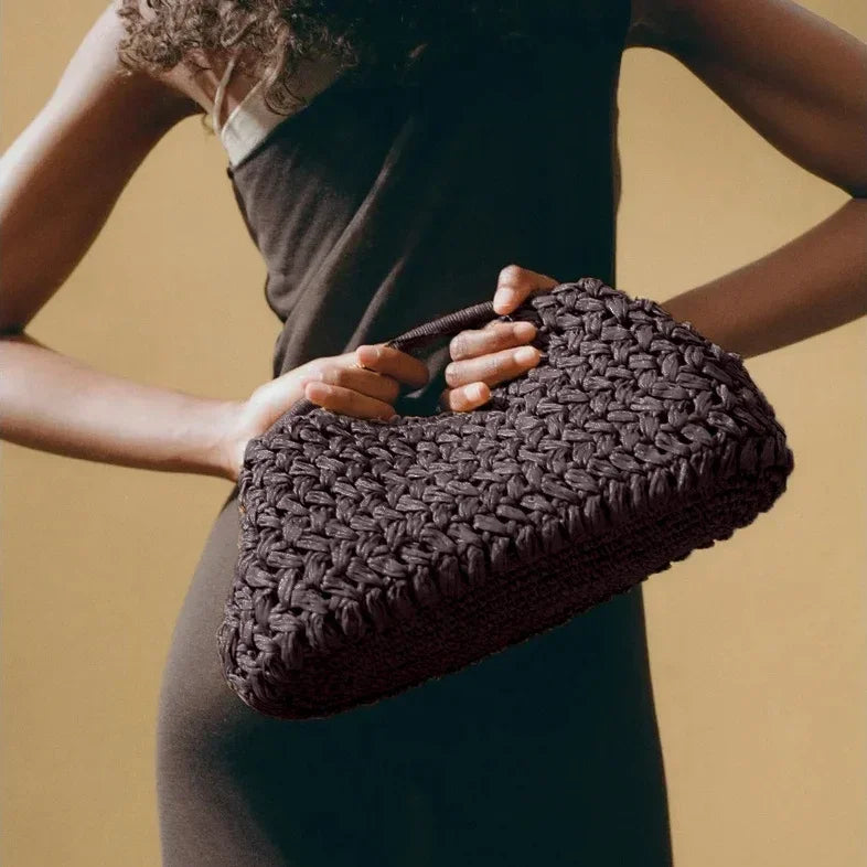 Woman holding a woven black Rovelli handbag against a neutral background