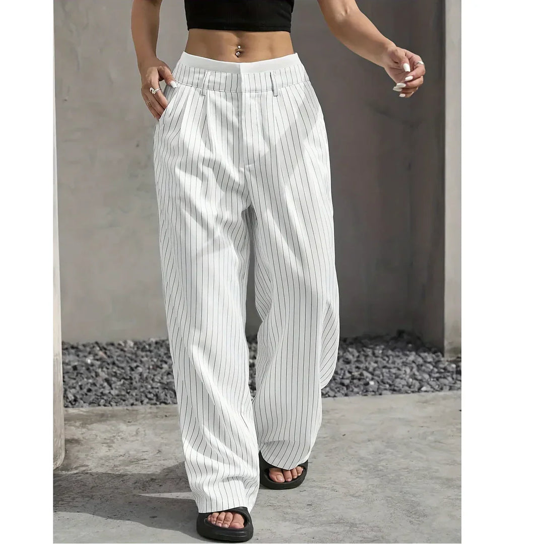 Woman wearing white pinstripe wide-leg pants, black crop top, and sandals outdoors for Rovelli